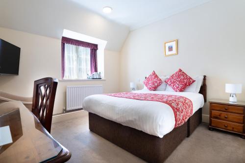a bedroom with a large bed with red pillows at Orton Hall Hotel & Spa in Peterborough