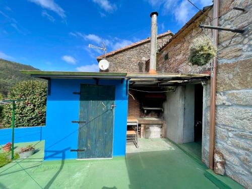 a house with a blue door and a patio at Casa do Cucharro en Playa de Soesto, Laxe in Laxe