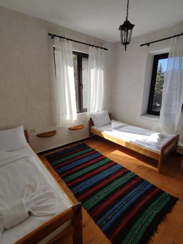 a bedroom with two beds and a rug at Кулинарна къща за гости СОФРИЦА in Hvoyna