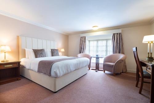 a bedroom with a bed and a desk and a chair at Orton Hall Hotel & Spa in Peterborough