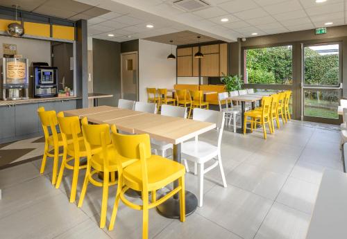 a dining room with yellow chairs and a table at B&B HOTEL Albi in Albi