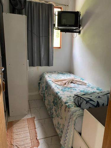 a small bedroom with a bed and a tv on the wall at Hotel Pousada Do Viajante in Erechim