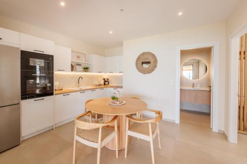 a kitchen with a wooden table and chairs and a kitchen with white cabinets at House Eleni in Agios Georgios Pagon