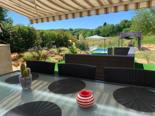d'une terrasse avec une table et une vue sur le jardin. dans l'établissement La grange en pierre - chic & piscine privée, à Queyssac