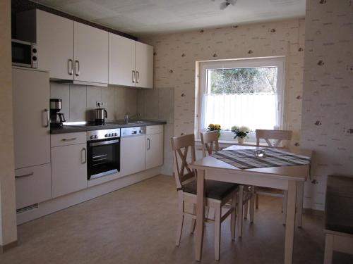 cocina con mesa, sillas y ventana en Ferienwohnung Schönhense, en Medebach