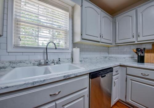 eine Küche mit weißen Schränken und einer Spüle und einem Fenster in der Unterkunft Bama Retreat - Sleeps 10, 5 Miles to Game Day Fun in Northport