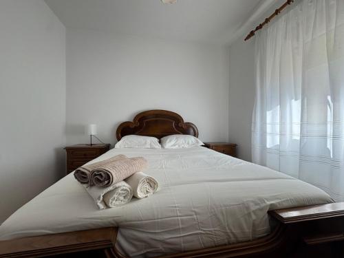 a bedroom with a bed with white sheets and towels at Casa Outeiro Polo 1 in Marinhas