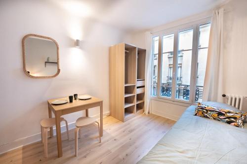 une chambre avec un lit, une table et un miroir dans l'établissement Beautiful studio near Eiffel Tower and Beaugrenelle, à Paris