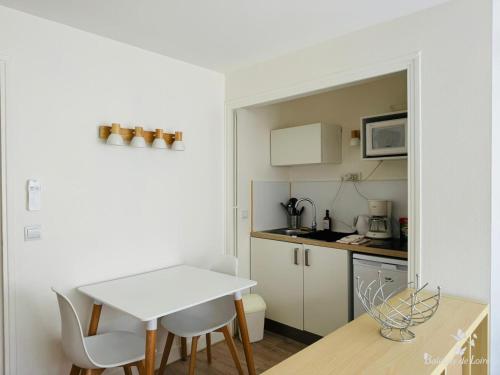 une petite cuisine avec une table et des chaises blanches dans l'établissement Studios Balcony de Loire, à Tours