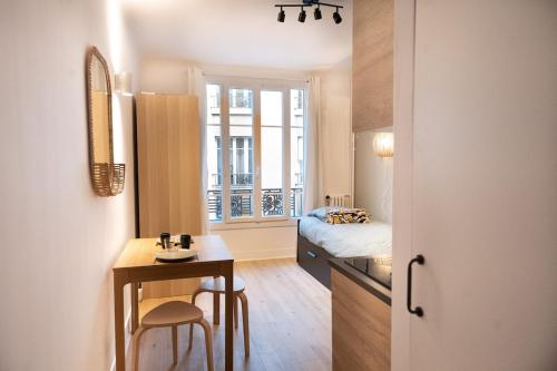 Cette petite chambre comprend un lit, un bureau et une table. dans l'établissement Beautiful studio near Eiffel Tower and Beaugrenelle, à Paris