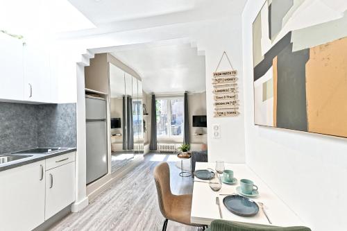 une cuisine avec des armoires blanches et une table et des chaises dans l'établissement Studio Terrasse vue incroyable sur Tour Eiffel, à Paris
