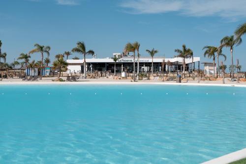 ein Swimmingpool vor einem Resort mit Palmen in der Unterkunft Modern Villa in Santa Rosalía with Rooftop View BY COELI HOME LIVING in Torre-Pacheco