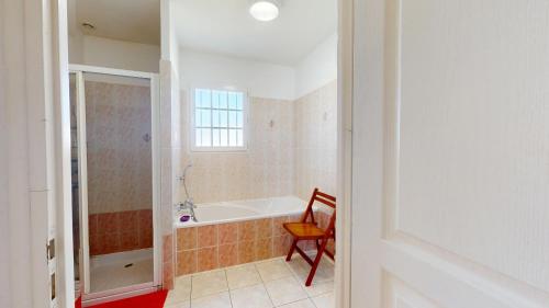 y baño con bañera y silla. en Le Clos du Cep, en Saint-Hilaire-de-Riez