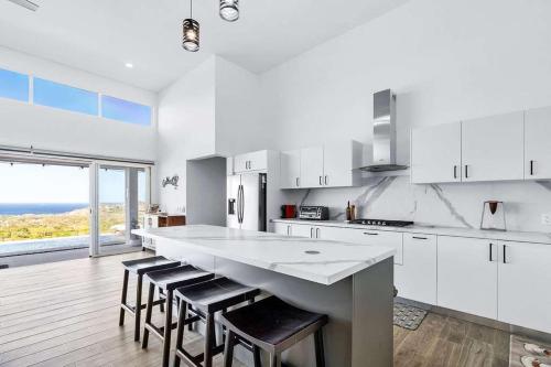 a kitchen with white cabinets and a large island with stools at Ocean View Villa & Private Pool in Mar Vista in Brasilito