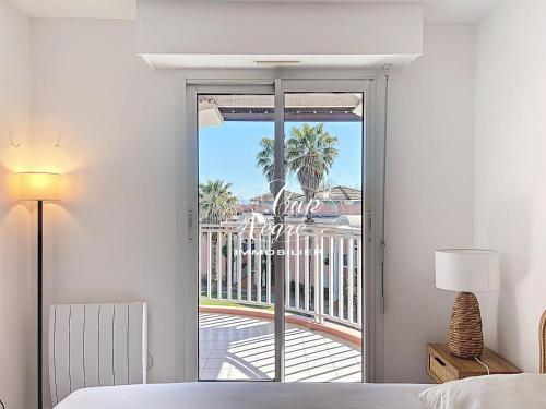 - une chambre avec une porte coulissante en verre donnant sur un balcon dans l'établissement Appartement classé 3 étoiles avec terrasse à 150 m plage de Cavalière - LE LAVANDOU, au Lavandou