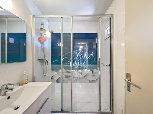 une douche avec une porte vitrée dans une salle de bain dans l'établissement Appartement classé 3 étoiles avec terrasse à 150 m plage de Cavalière - LE LAVANDOU, au Lavandou
