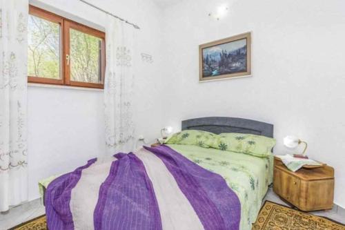 a bedroom with a bed with a purple blanket at Holiday home in Dolenja Vas - Istrien 51824 in Dolenja Vas