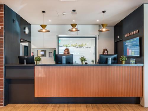 a woman sitting at a counter in a waiting room at B&B HOTEL Zürich Airport in Rümlang