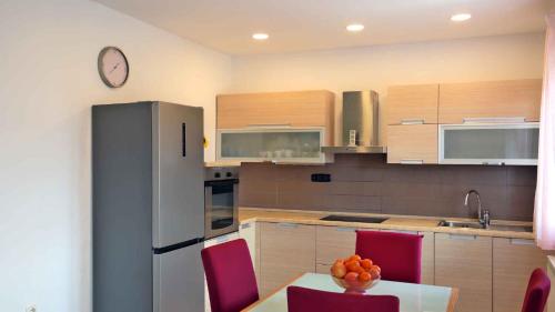 a kitchen with a table with red chairs and a refrigerator at Apartment in Cavle 54436 in Čavle