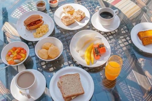 a glass table with plates of breakfast foods and coffee at Pousada Dunas da guarda in Guarda do Embaú