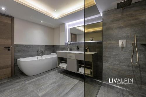 a bathroom with a tub and a sink and a mirror at LIVALPIN Relaxe in Garmisch-Partenkirchen