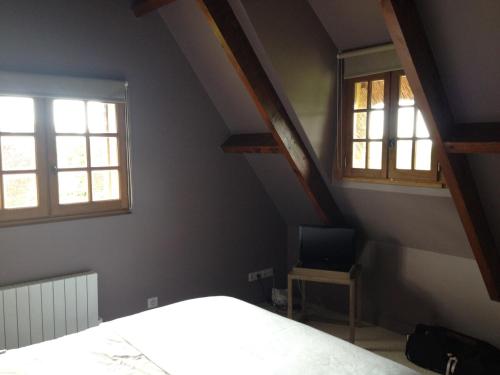 - une chambre avec deux fenêtres, un lit et une chaise dans l'établissement Chaumière de charme avec piscine, à Tourgéville