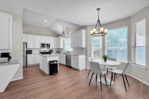 a kitchen with white cabinets and a table and chairs at Modern 4BR Gem Chic Comfort in Austin home in Austin