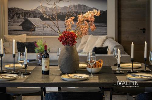 a table with a bottle of wine and a vase with flowers at LIVALPIN Relaxe in Garmisch-Partenkirchen