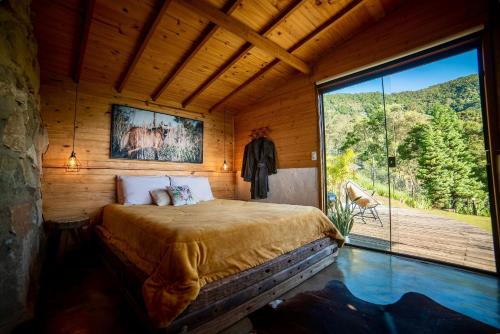 a bedroom with a bed and a large window at Cabana Lobo Guará in Paiol Grande