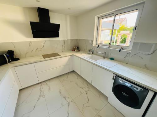 a white kitchen with a sink and a dishwasher at La Villa Lumière in Bourg-lès-Valence