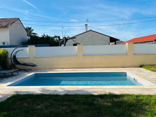 a swimming pool in a yard next to a fence at La Villa Lumière in Bourg-lès-Valence