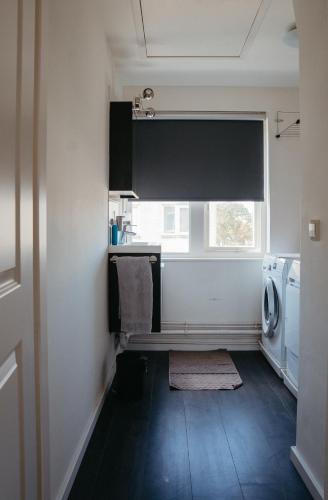 a laundry room with a sink and a window at Perla di Robbie in Zandvoort