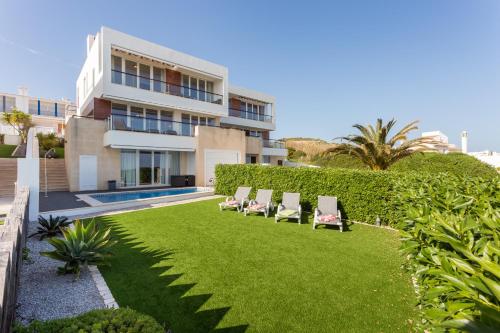 a row of chairs on a lawn in front of a building at CoolHouses Algarve Luz, Ocean front 4 Bed house w/ pool, Casa da Pipa in Luz
