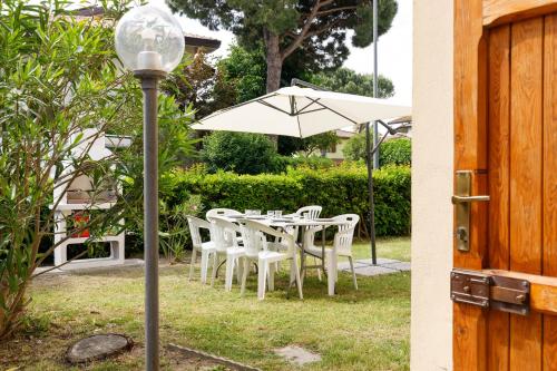 a table with white chairs and an umbrella at La Casa Del Mare Private Parking And WiFi in Lido Adriano