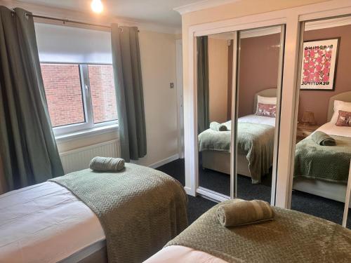 a bedroom with two beds and a mirror at 3BR Flat Sleeps 6 West End Sights Driveway in Glasgow
