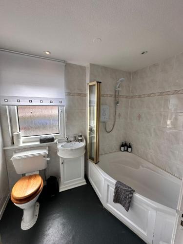 a bathroom with a tub and a toilet and a sink at 3BR Flat Sleeps 6 West End Sights Driveway in Glasgow