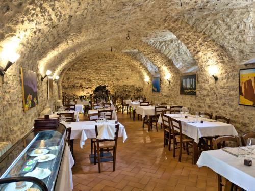 a restaurant with white tables and chairs in a stone wall at Abbazia dei Santi Felice e Mauro in Castel San Felice