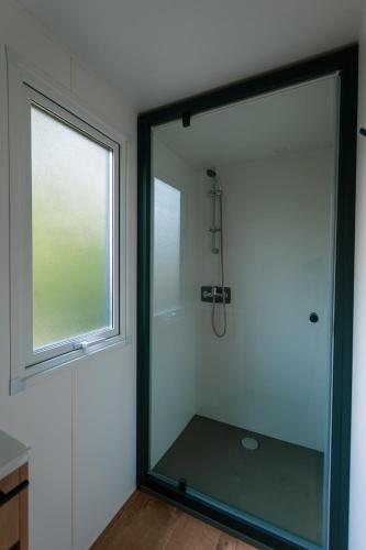 La salle de bains est pourvue d'une grande douche en verre et d'une fenêtre. dans l'établissement Camping les Avignon - la Laune, à Villeneuve-lès-Avignon