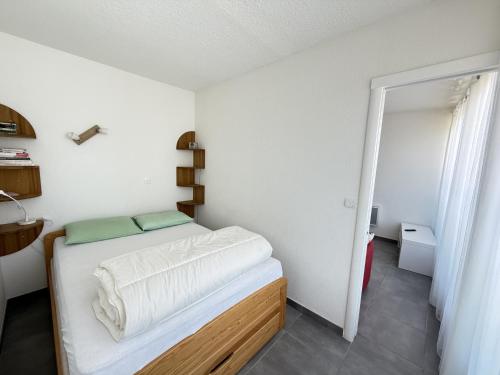 Cette petite chambre comprend un lit avec des draps blancs. dans l'établissement Sol-y-Days Fleurie 1 Appartement Grande Terrasse et Parking, à La Grande Motte