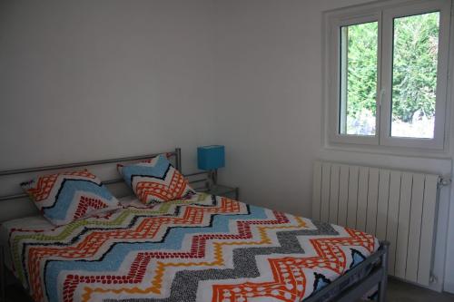 une chambre avec un lit avec une courtepointe colorée dessus dans l'établissement Le Carrouge, à Lacapelle-Biron