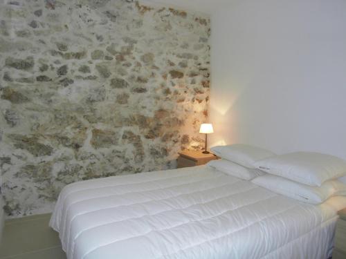 a bedroom with a white bed and a stone wall at La Ferronnerie Cassis centre in Cassis