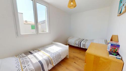 une chambre avec deux lits et une fenêtre dans l'établissement Le Nid de la Mouette, à Saint-Hilaire-de-Riez