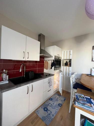 a kitchen with white cabinets and red tiles at Petite bulle de mer, à quelques pas du rivage in Lion-sur-Mer