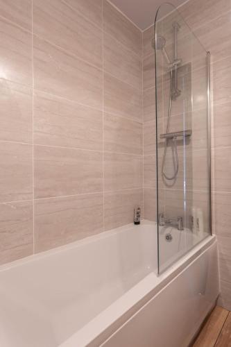 a bath tub with a glass shower in a bathroom at Fisherman's Cottage by the sea in Morecambe