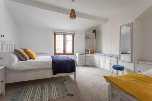a white bedroom with a bed and a blue stool at Fisherman's Cottage by the sea in Morecambe