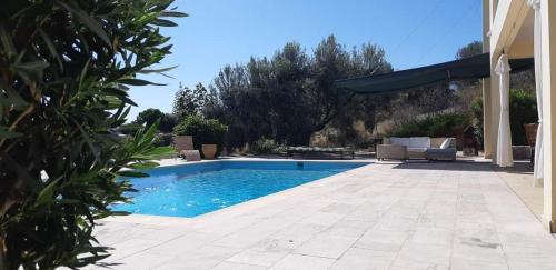 a swimming pool in a yard with a patio at Villa Oliva in Porto Heli