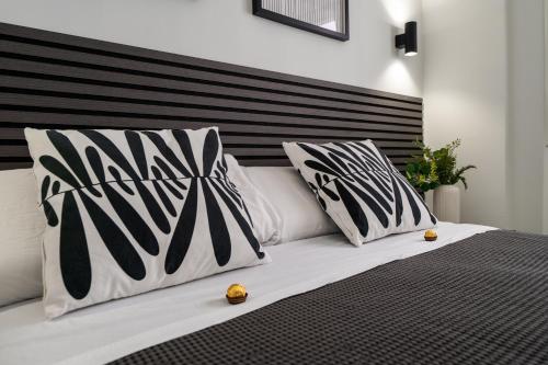 a bed with black and white pillows on it at Las Flores Luxury Apartment in Málaga