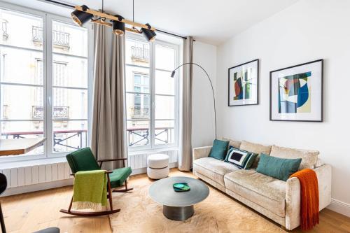 un salon avec un canapé et deux fenêtres dans l'établissement GuestReady - Parisian charm near Notre-Dame, à Paris