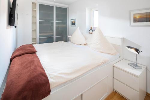 a white bedroom with a bed with a window at Sommertraum im 3 Jahreszeiten in Norderney