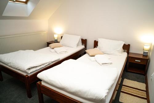 two twin beds in a room with white sheets at Penzión Zvala in Pichne